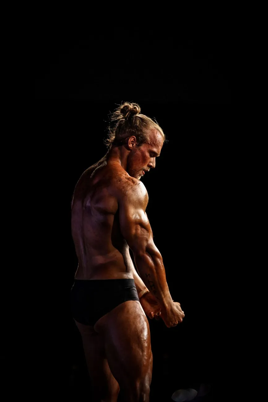 Athlete in a back pose against a black background